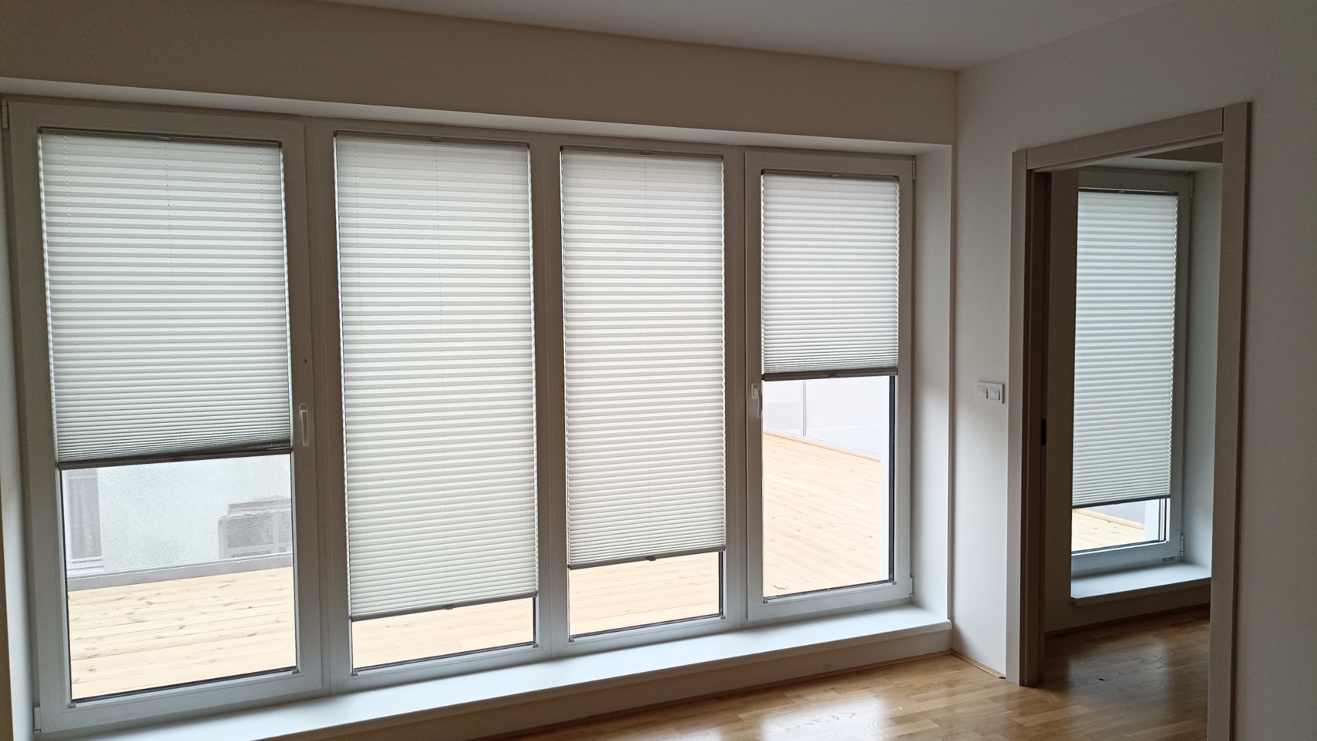 Světlé plisé žaluzie na velkých prosklených plochách, realizace Praha 10, moderní stínění interiéru.