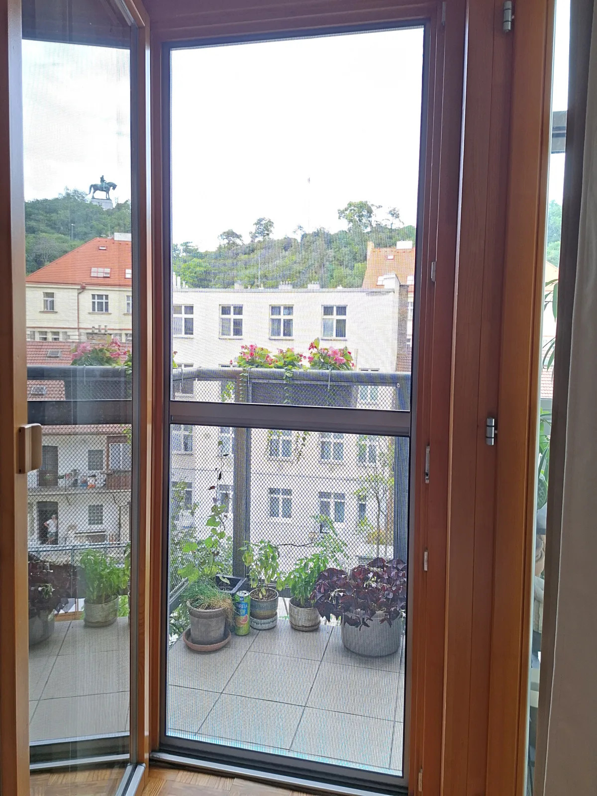Dveřní síť na panty s PET síťovinou při pohledu z interiéru na balkon